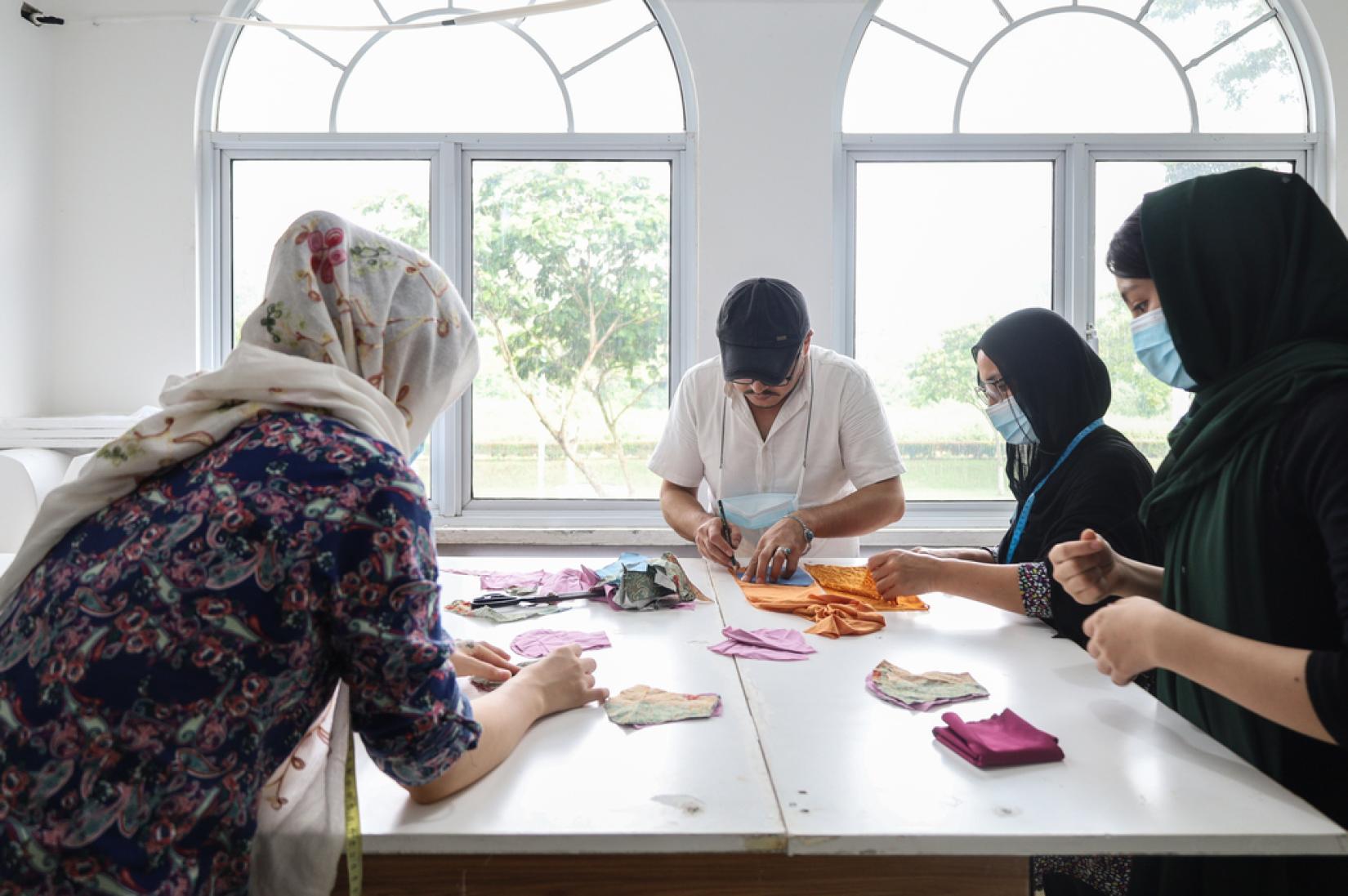 Three women and one man are learning handicraft in a classroom