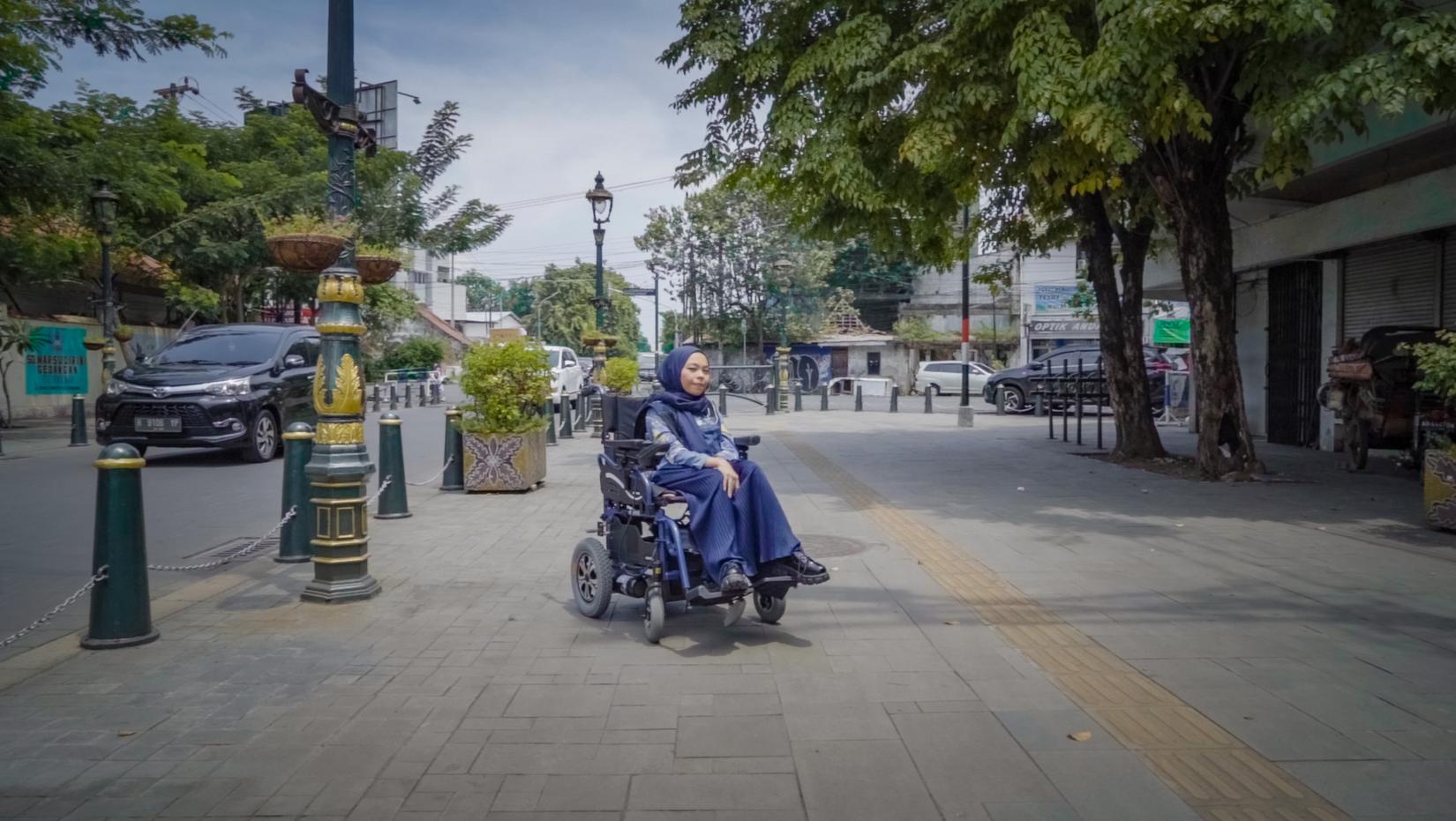 A woman on a wheelchair by the street
