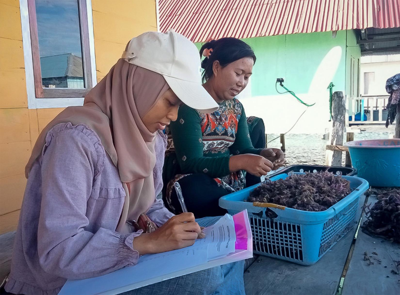 Ristifah writing and recording data from a local woman