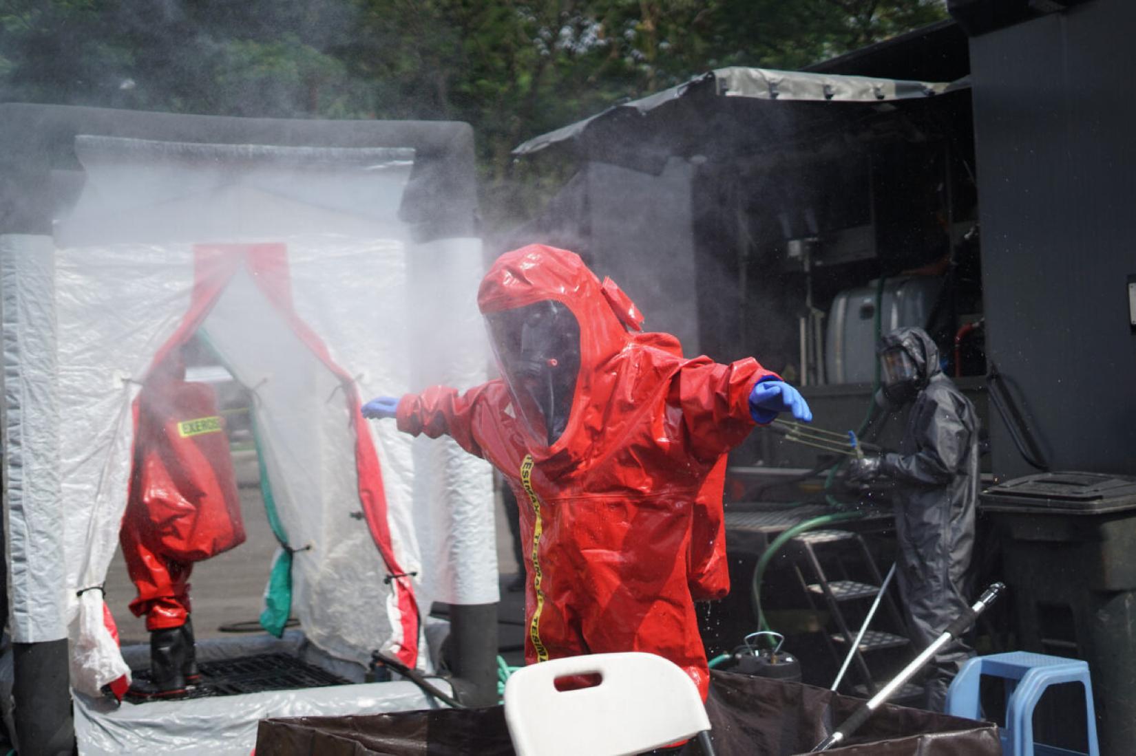 A person in a hazmat suit being sprayed