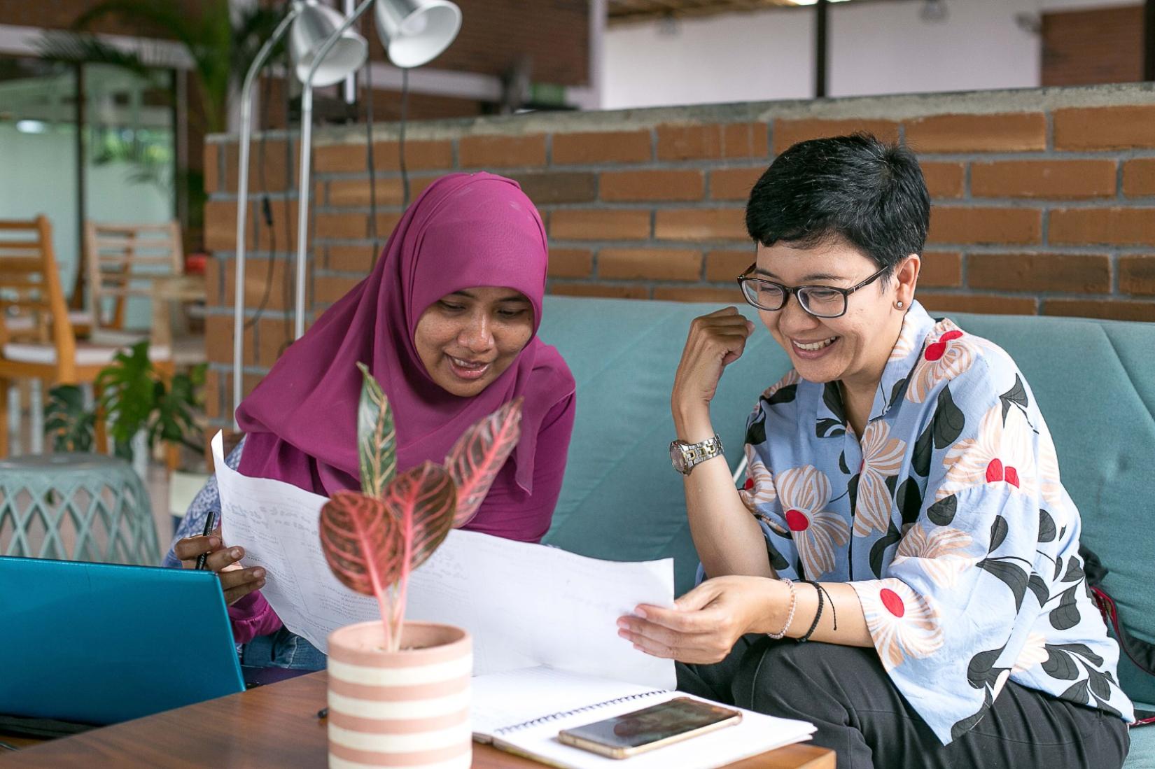 Two women looking at a piece of paper in an office