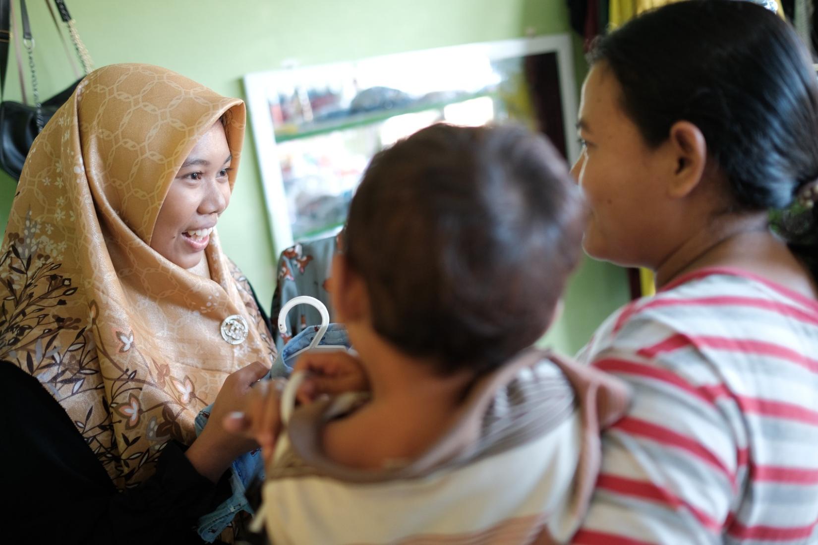 Ratna talking to a mother carring her son