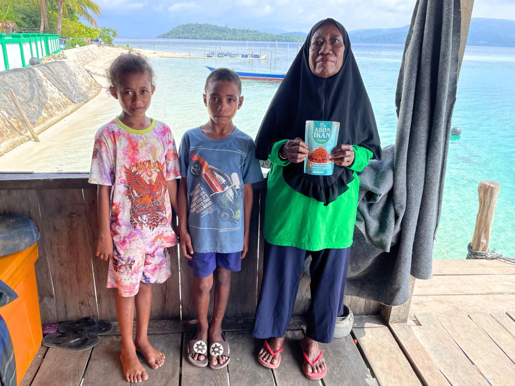 A women and children posing with a pack of fish floss