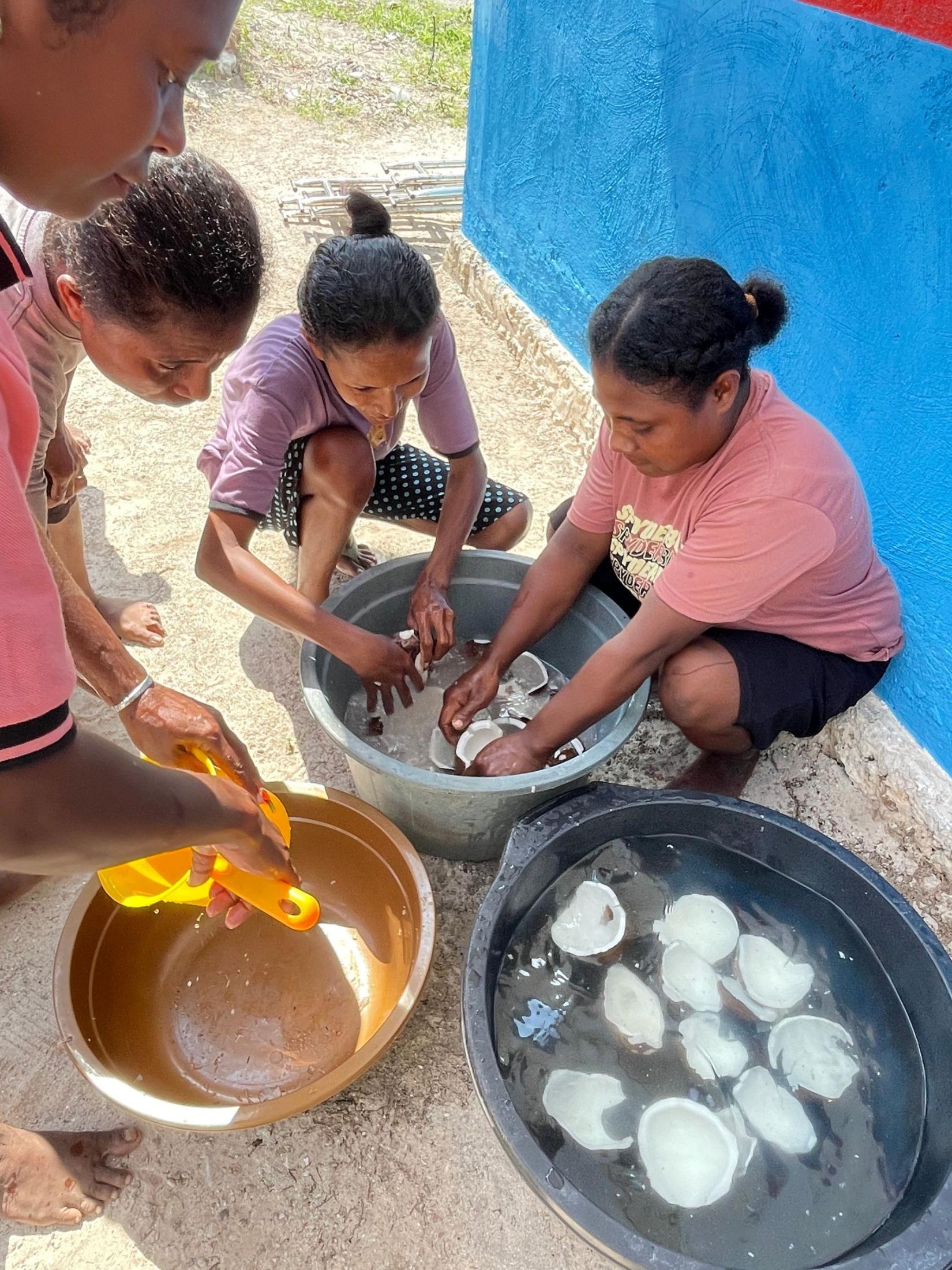 Three women washing coconuts