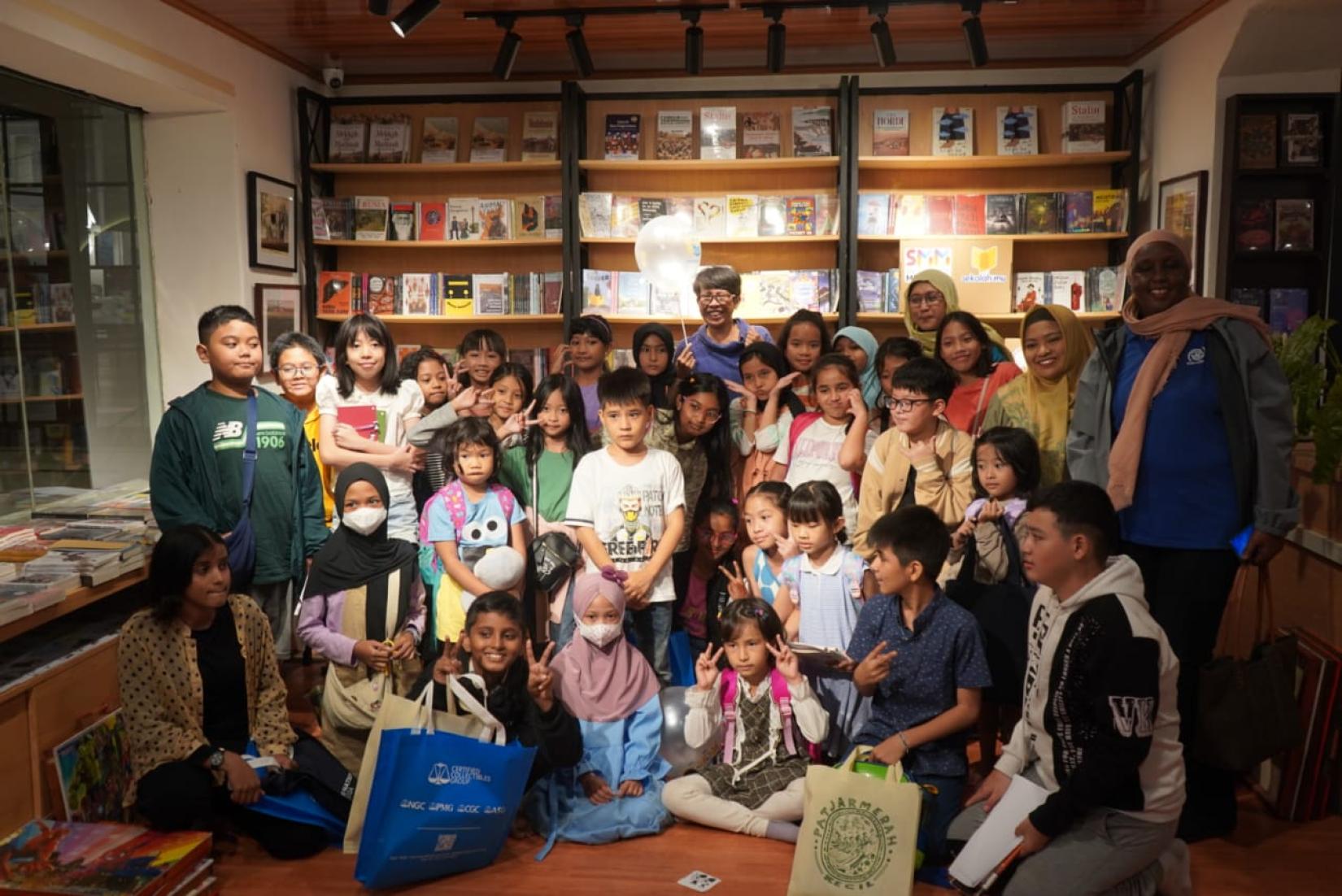 Dozens of children posing in a room after participating in a workshop