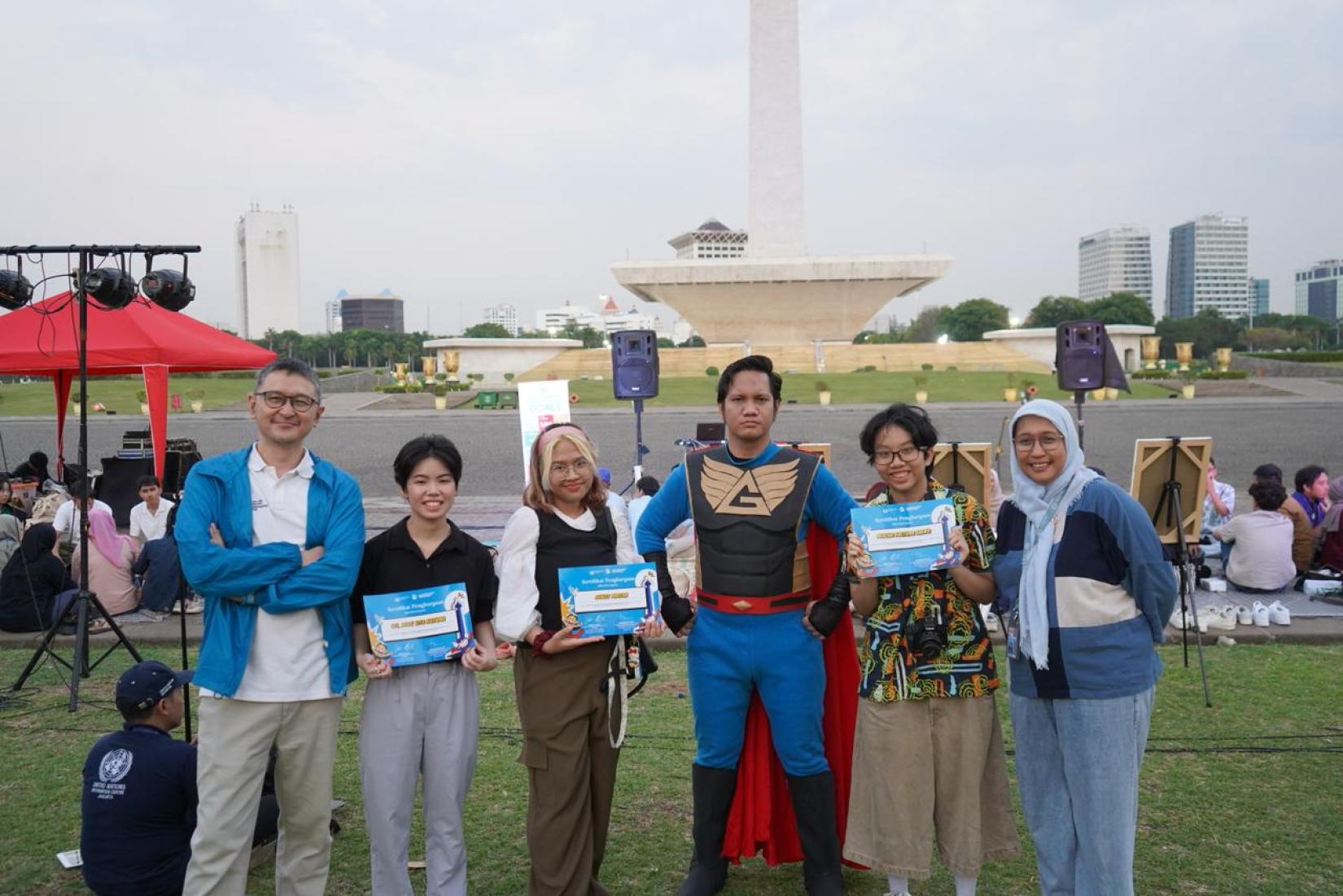 Six people poses in front of Monas