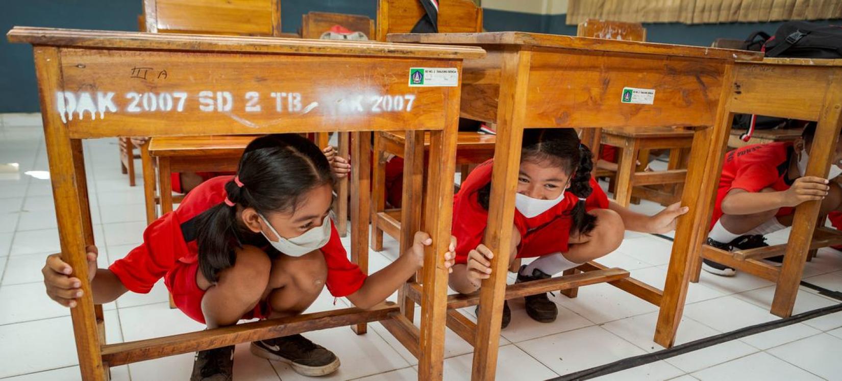 Children duck under their school tables