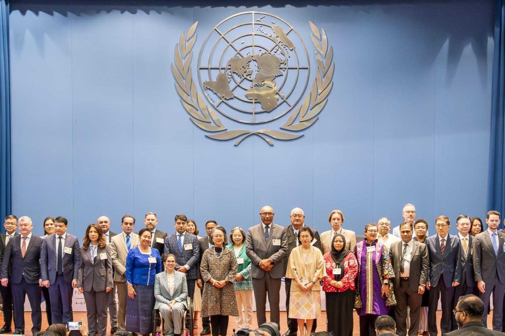 Dozens of high-level people standing on a stage with UN logo as the background