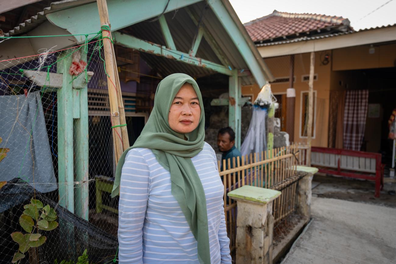A woman in Hijab standing in front of her house