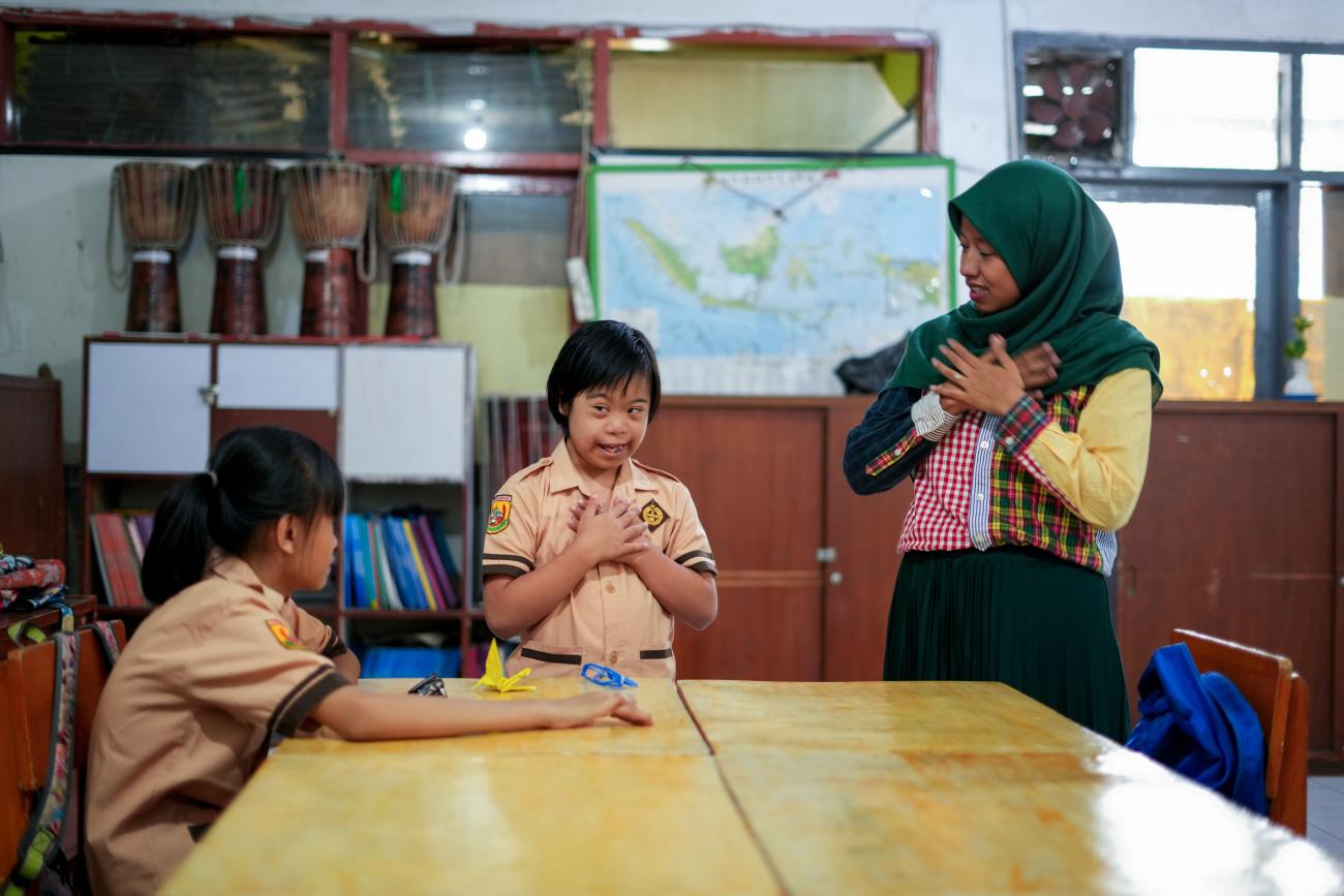 Two girls with special needs in school uniform learning about their body from a teacher in hijab in a classroom