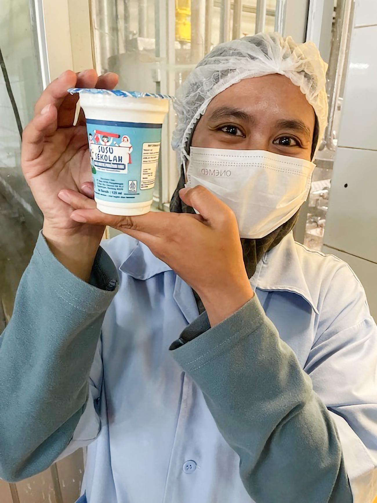 A worker at the KPBS cooperative holds up a dairy product.