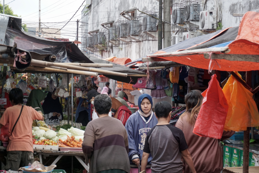 Hiruk pikuk kondisi pasar tradisional dimana orang-orang tampak sibuk berbelanja.