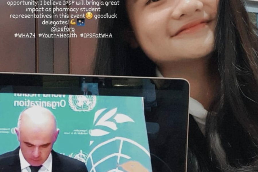 Seorang wanita tersenyum cerah ke kamera berpose dengan memegang laptopnya yang menunjukan siaran langsung konferensi online.