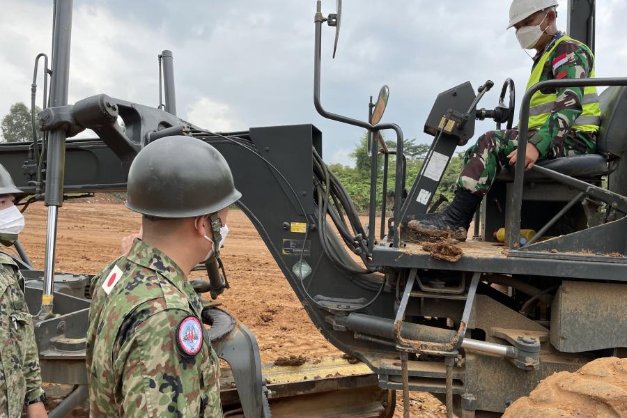 A man wearing an official Indonesian army uniform rides heavy equipment. 