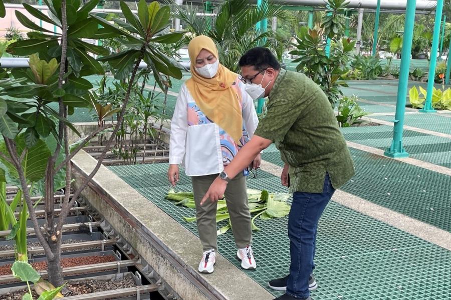 One woman and a man stand in front of the MM 2100 Industrial Town wastewater treatment plant.