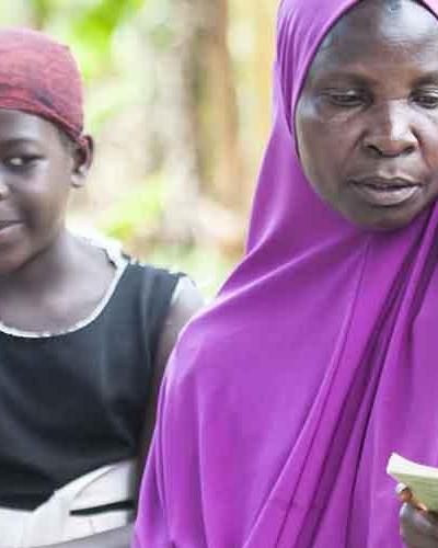 Joweria Nabukenya, a widow, reads with some of her 8 grandchildren in Isingiro District. Nabukenya has been on Key Family Care Practices with support from UNICEF. She has a routine where she reads with the children, and plays with them as they learn.