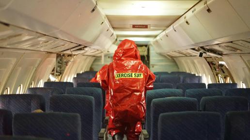 A person wearing orange hazmat suit walking inside of a plane